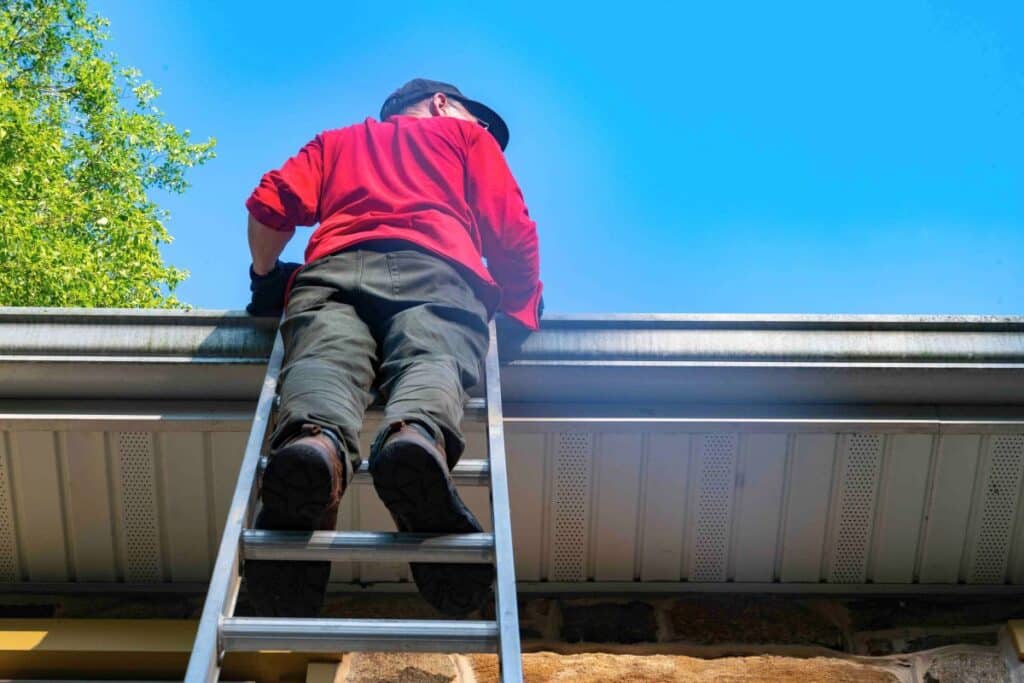 homeowner cleaning gutters on a ladder showing typical gutter cleaning responsibility