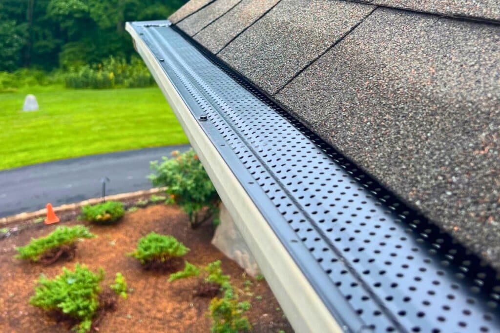 Metal gutter guard installed along roof edge on residential home to prevent leaves and debris buildup