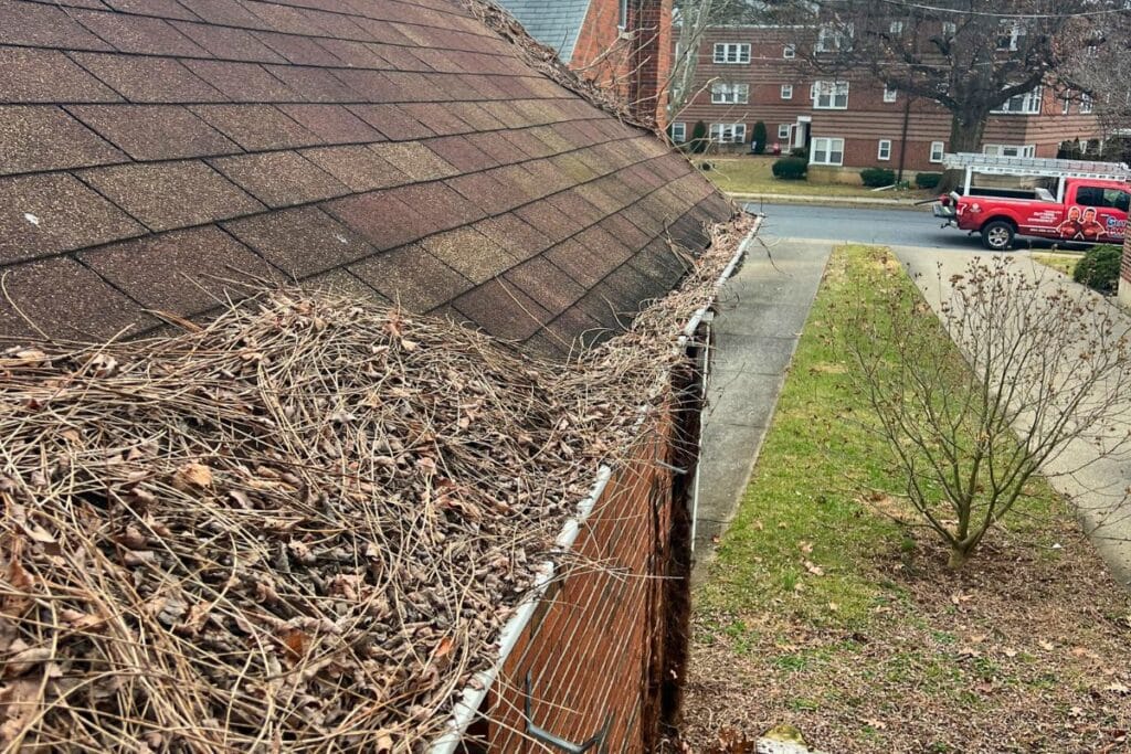 clogged gutters filled with leaves and debris on residential home